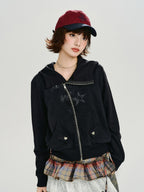 Woman wearing a black zip-up hoodie with the hood down, displaying the graphic print and front pockets.