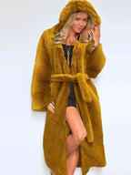Woman wearing a long mustard yellow hooded faux fur coat with a belt