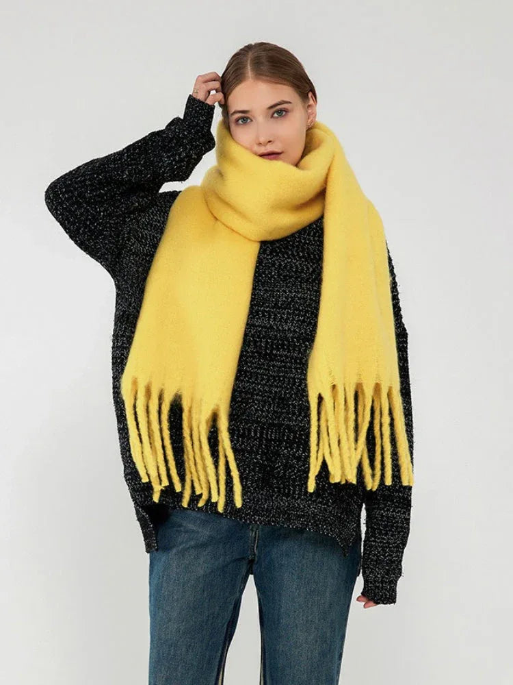 Front view of a woman with a bright yellow fringed scarf wrapped around her neck.