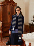 Woman in a navy knit sweater and striped scarf indoors.