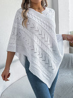 Woman wearing a white knit poncho with a V-neck and asymmetrical hem.
