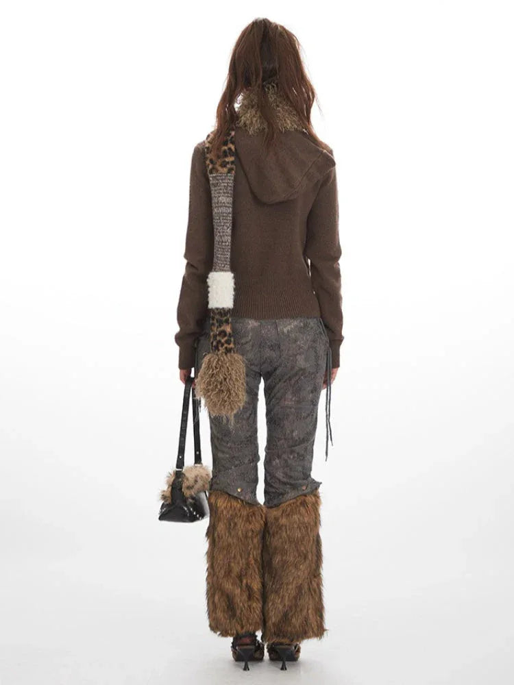 Woman wearing a brown turtleneck sweater, patterned pants with faux fur leg warmers, a leopard print scarf, and a black handbag