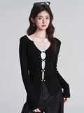 Close-up of a black knit top with lace detail and decorative buttons