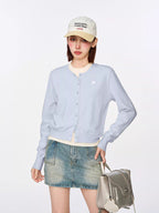 Woman wearing a light blue cropped knit cardigan with a crew neck and long sleeves