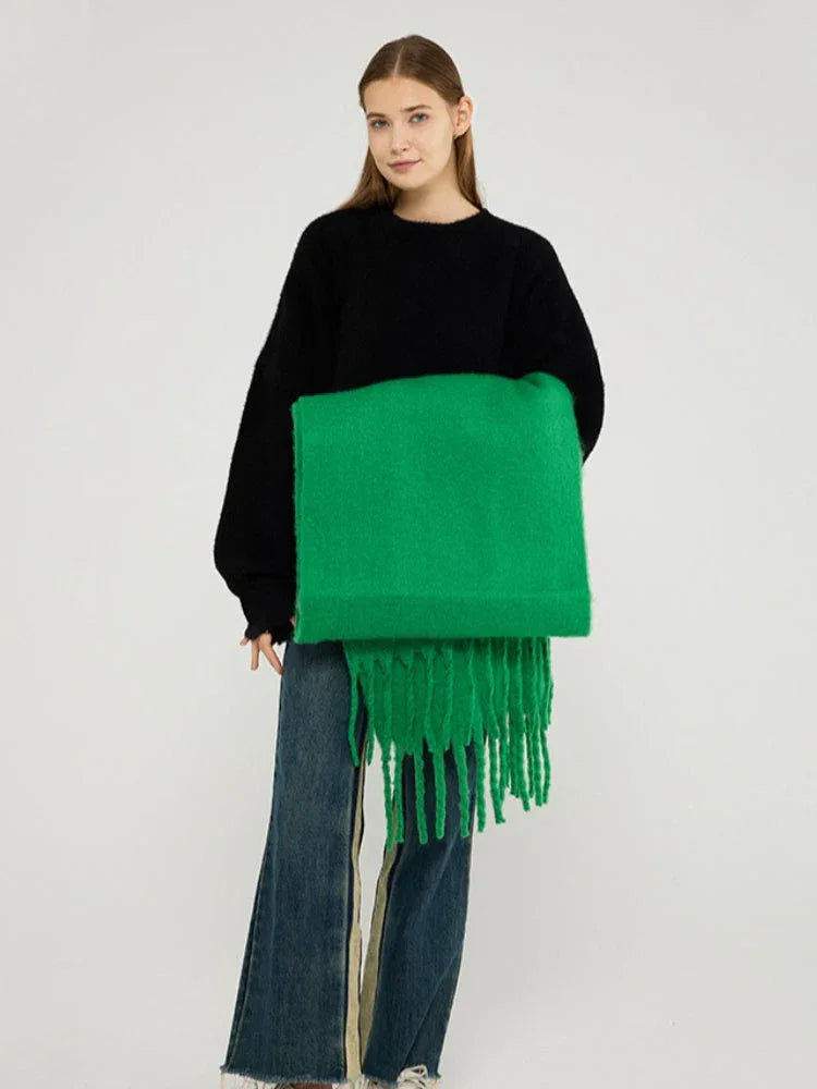 Woman holding a bright green brushed wool blend scarf with fringe trim.