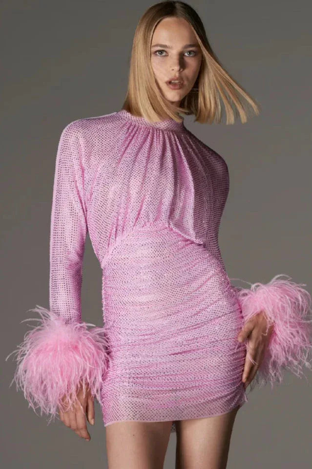 Woman wearing a sparkling pink mini dress with long sleeves and feather cuffs Main image