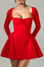 Model posing in a red long-sleeved dress with a sweetheart neckline and bow detail