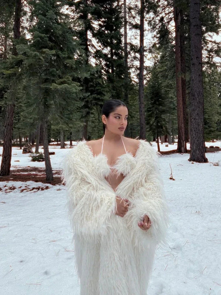 Woman in a white faux fur coat in a snowy woodland environment