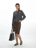 Model wearing a grey cardigan, brown skirt, and knee-high socks, with a tote bag.