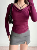 Woman wearing a plum fitted long-sleeve top with a cowl neck, accessorized with a black shoulder bag.
