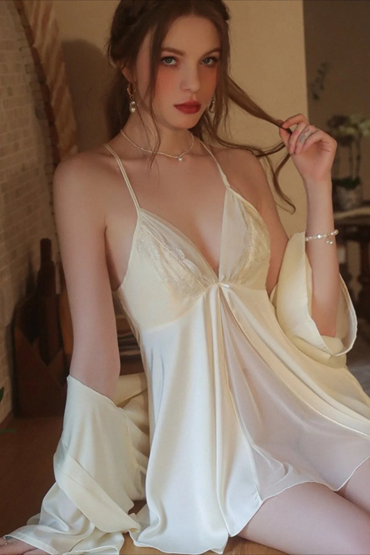 Close-up of a woman in a cream satin chemise and robe, showing the lace bust detail.