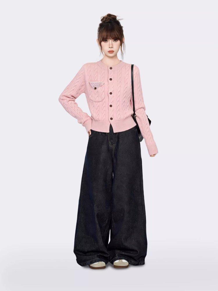 Full body shot of a woman in a pink cable knit cardigan and wide-leg jeans