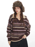 Close-up of a woman wearing a brown striped knit sweater with a v-neck and collar detail, and a brown faux fur hat with ear flaps.