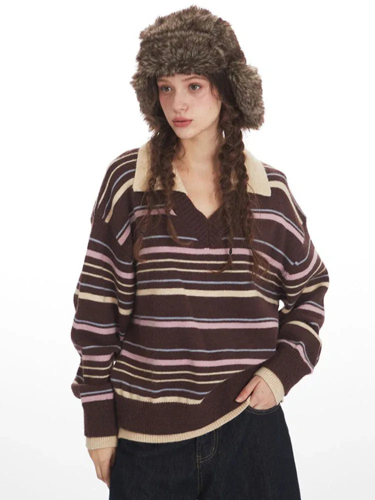 Close-up of a woman wearing a brown striped knit sweater with a v-neck and collar detail, and a brown faux fur hat with ear flaps.