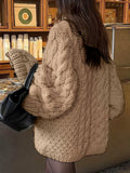 Rear view of a woman in a beige chunky knit sweater with voluminous sleeves.