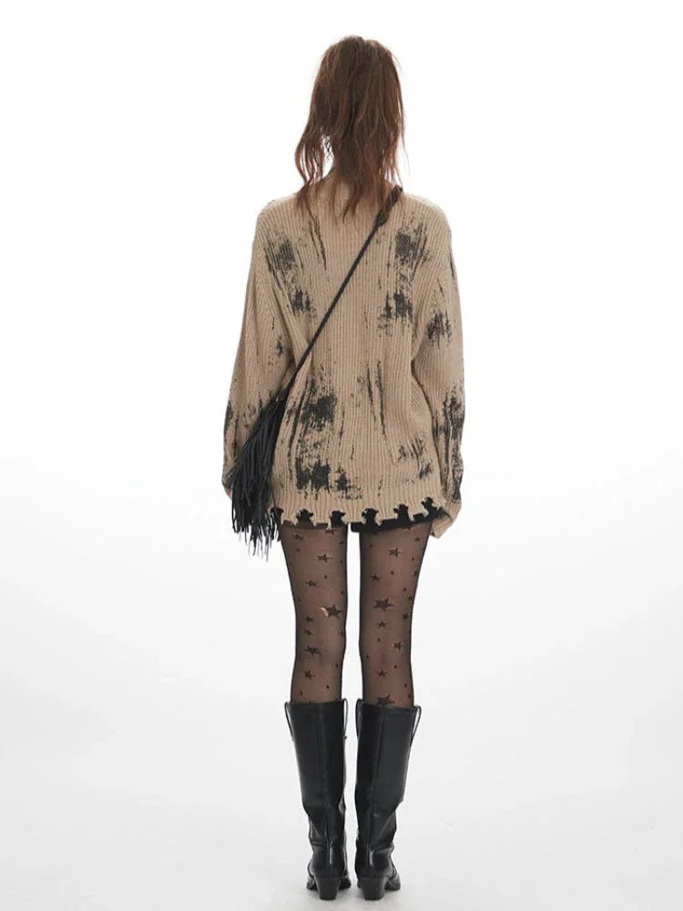Back view of a tan knit cardigan with abstract black print and distressed hem.
