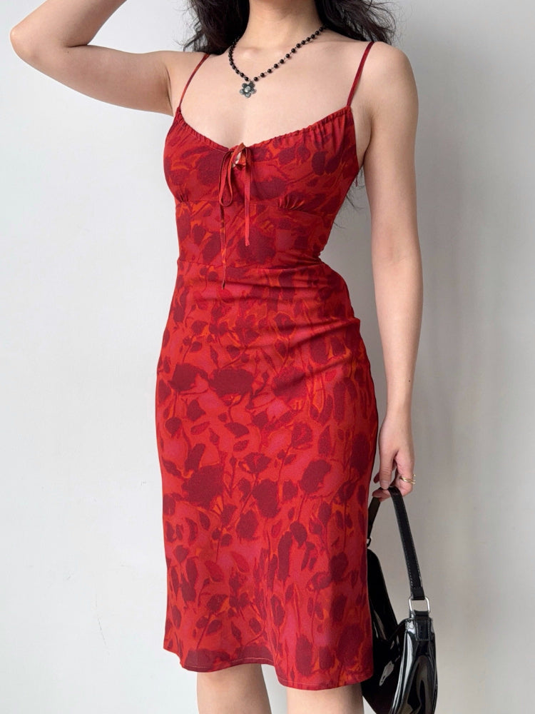 Woman wearing a red floral print midi dress with spaghetti straps and a self-tie front