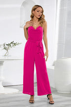 Model wearing a fuchsia wide leg jumpsuit with a self-tie belt and cowl neckline.