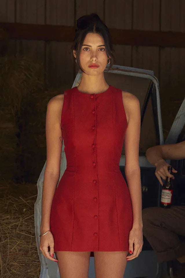 Woman standing by a vintage truck in a red sleeveless dress