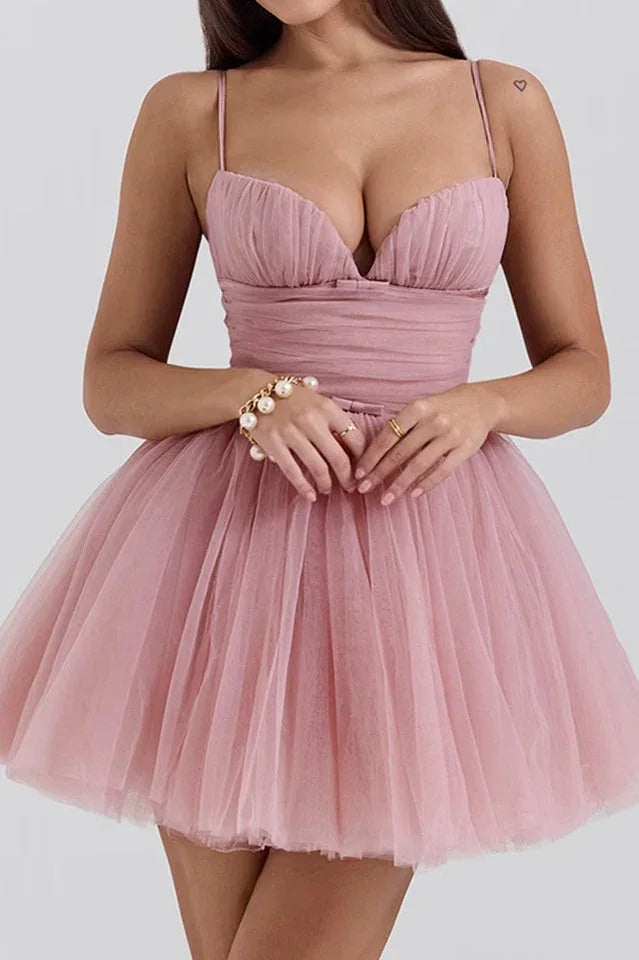 Woman wearing a short pink tulle dress with ruched bodice and spaghetti straps. Main image