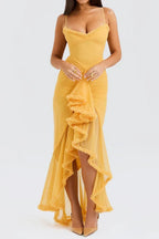 Close-up front view of a woman in a yellow ruched mesh evening dress with spaghetti straps and tiered ruffles.