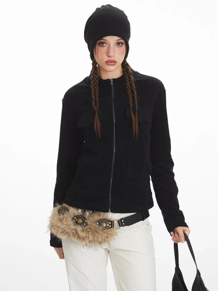 Close-up of a woman wearing a black zip-up fleece jacket, white pants, and a black beanie.