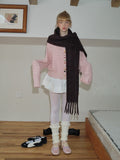 Full body shot of a woman in a pink cardigan, white skirt, and dark brown scarf.
