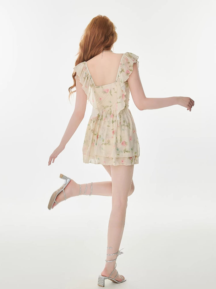 Back view of a woman wearing a cream floral print chiffon mini dress with ruffle trim.