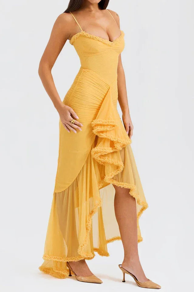 Close-up side view of a woman in a yellow ruched mesh evening dress with spaghetti straps and ruffled detailing.
