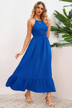 Full body shot of a woman in a royal blue smocked halter maxi dress with a tiered ruffle hem.