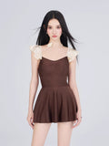 Full body shot of a woman modeling the brown and cream swimsuit with a flounced skirt.