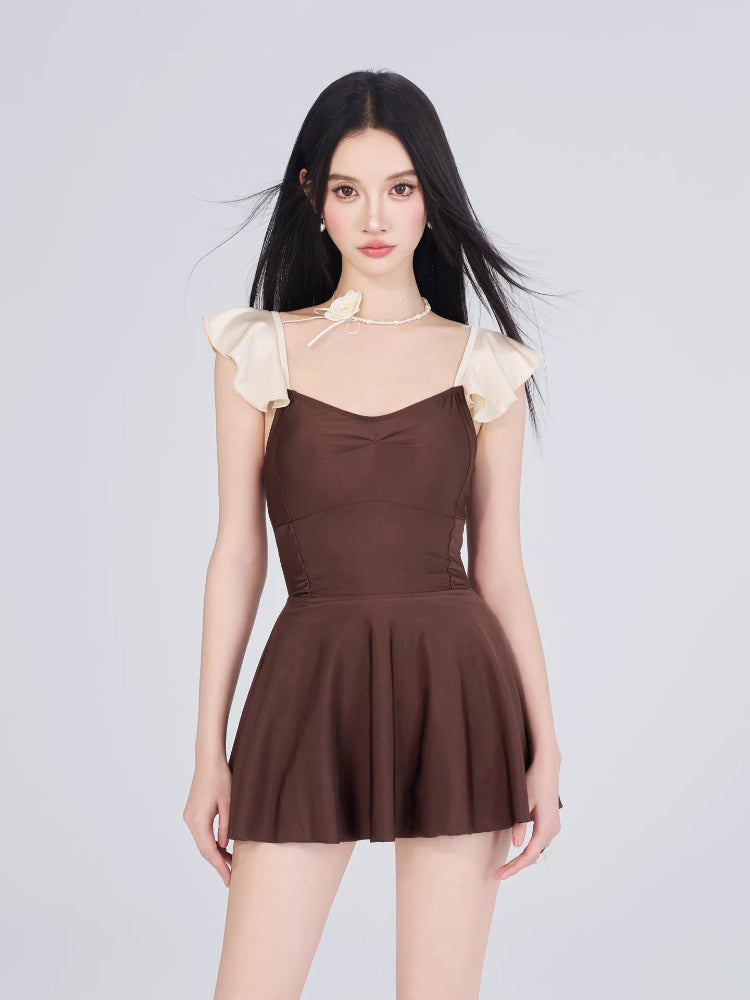 Full body shot of a woman modeling the brown and cream swimsuit with a flounced skirt.