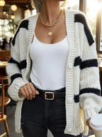 A woman styled in a white and black striped knit cardigan, paired with a white camisole and black belt, for a casual outfit.