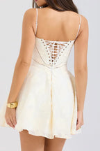 Back view of a woman in a white mini dress featuring a detailed lace-up back.