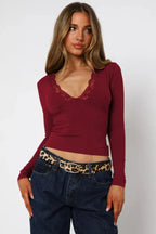 Woman wearing a burgundy long-sleeve top with lace trim at the neckline.