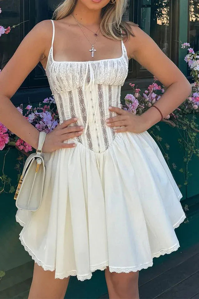 Woman in a white dress with a corset bodice and lace details, holding a white handbag.