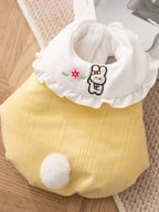 Close-up of a yellow pet vest with a white ruffled collar featuring embroidered bunny and flower details