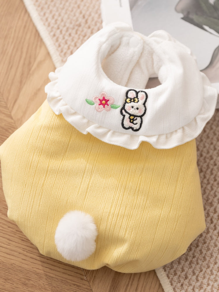 Close-up of a yellow pet vest with a white ruffled collar featuring embroidered bunny and flower details