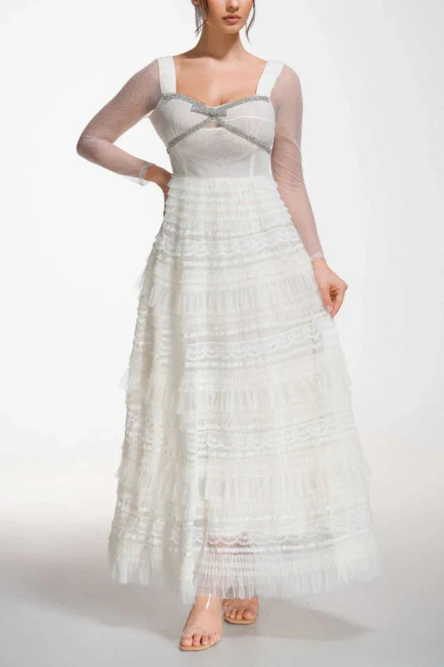Side view of a woman in a white long-sleeved gown with a tiered skirt