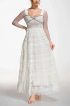 Side view of a woman in a white long-sleeved gown with a tiered skirt