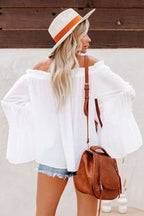 Back view of a woman in a white off-the-shoulder blouse, showcasing the ruffled bell sleeves.