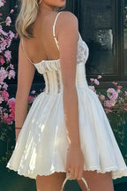 Back view of a white spaghetti strap dress with a lace bodice and short skirt.