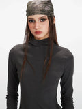 Model with a bandana and dark grey mock neck long sleeve top.