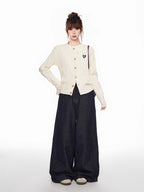 Full-body shot of a woman in a cream cable knit cardigan and dark wide-leg jeans, showcasing the garment's fitted silhouette and casual styling.