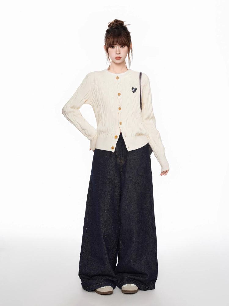 Full-body shot of a woman in a cream cable knit cardigan and dark wide-leg jeans, showcasing the garment's fitted silhouette and casual styling.