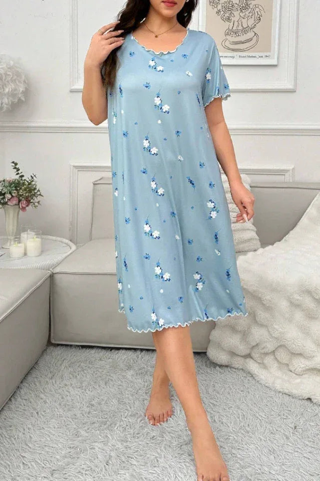 Full body shot of a woman in a light blue floral print nightgown standing indoors.