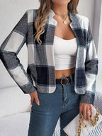 Woman posing in a blue and white plaid cropped jacket with denim jeans.