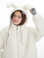 Close-up of a woman's face and upper body wearing a white fuzzy fleece hooded jacket with bunny ears, showing the texture of the fabric.