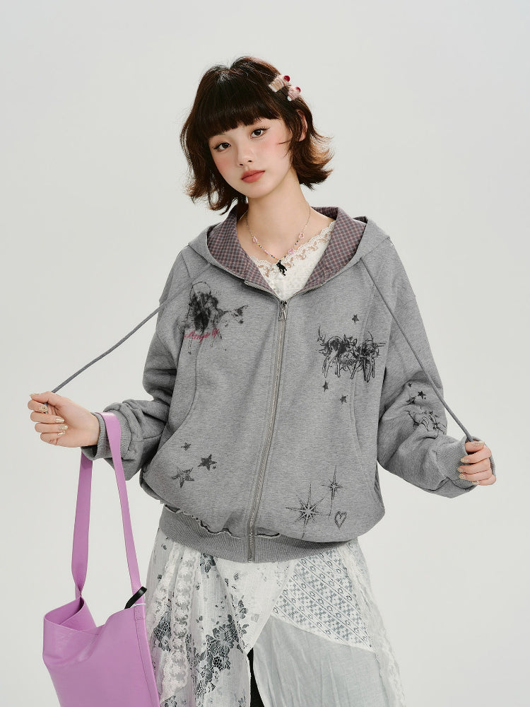 Woman wearing a grey graphic print zip-up hoodie with a checkered interior lining.