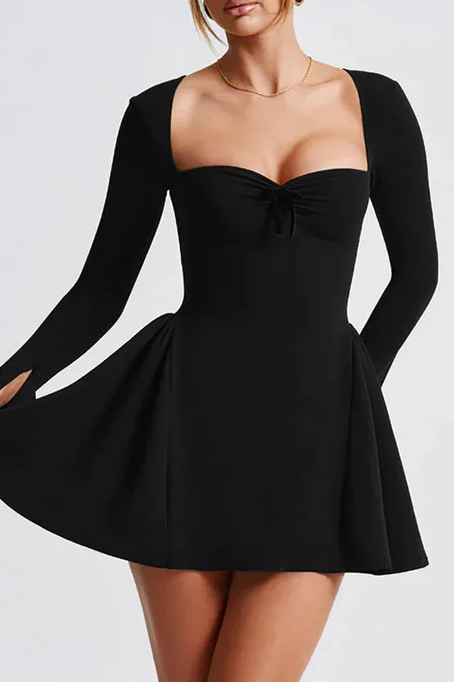 Woman wearing a black fit and flare dress with a sweetheart neckline and long sleeves